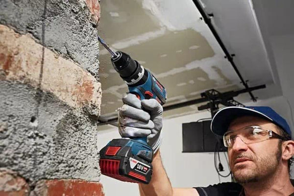 BOSCH GSB 18V-60 C Cordless Impact Drill: Professional drilling into masonry brick wall.