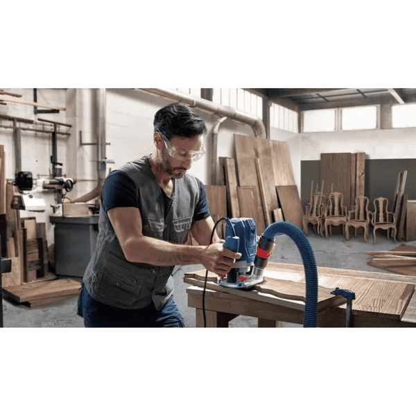 Man using Bosch GOF 130 Professional Router in workshop. Woodworking with professional tools.