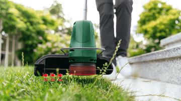 Bosch EasyGrassCut 18V-230 cordless grass trimmer cutting grass along sidewalk edge. Lawn care tool for easy edging.